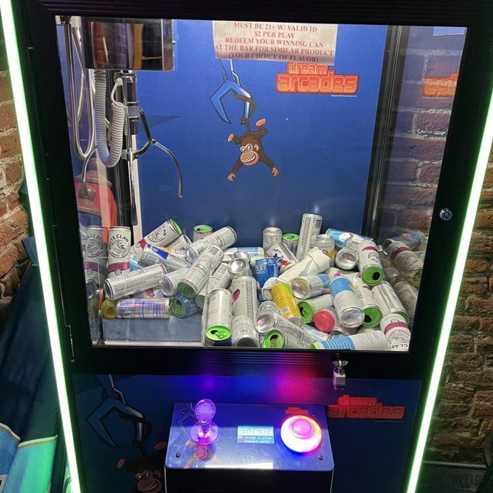 A claw machine filled with various empty beverage cans, including White Claw, at Swanky's Vittles and Libations.