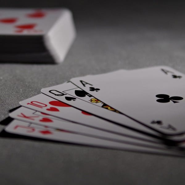 A fanned hand of playing cards, including a royal flush, on a dark table at Swanky's.