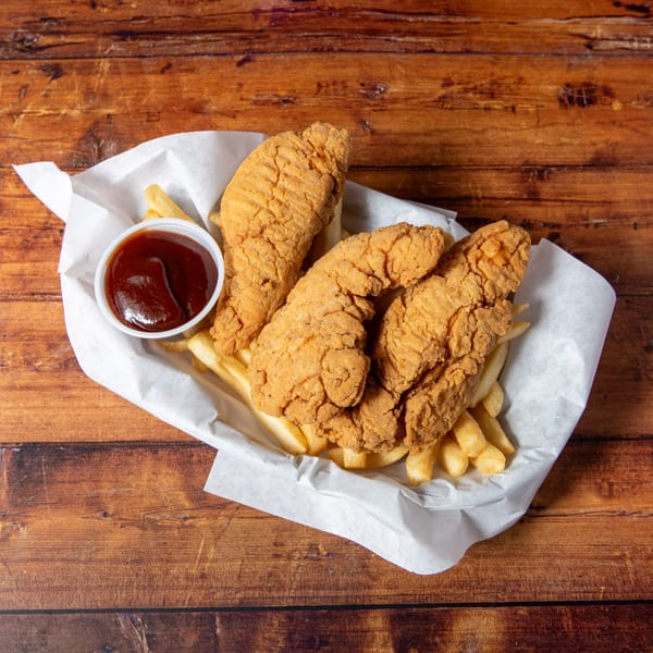 Crispy fried chicken tenders and golden french fries with a side of BBQ sauce in a white paper-lined basket.