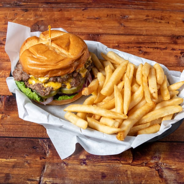 A Swanky's Vittles and Libations double cheeseburger with lettuce, pickles, and onions, served with fries.
