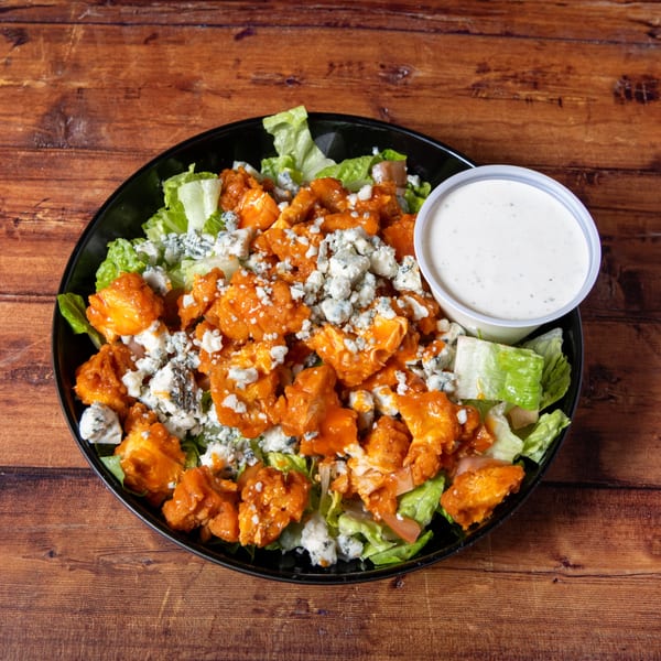 Buffalo chicken salad with blue cheese crumbles and a side of ranch dressing.